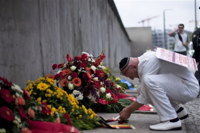 Achim von Almrich lights a candle at the Berlin Wall Memorial at Bernauer Strasse in Berlin on Saturday. Germany marks the 50th anniversary of the day, communist East Germany sealed itself off behind the Berlin Wall. 